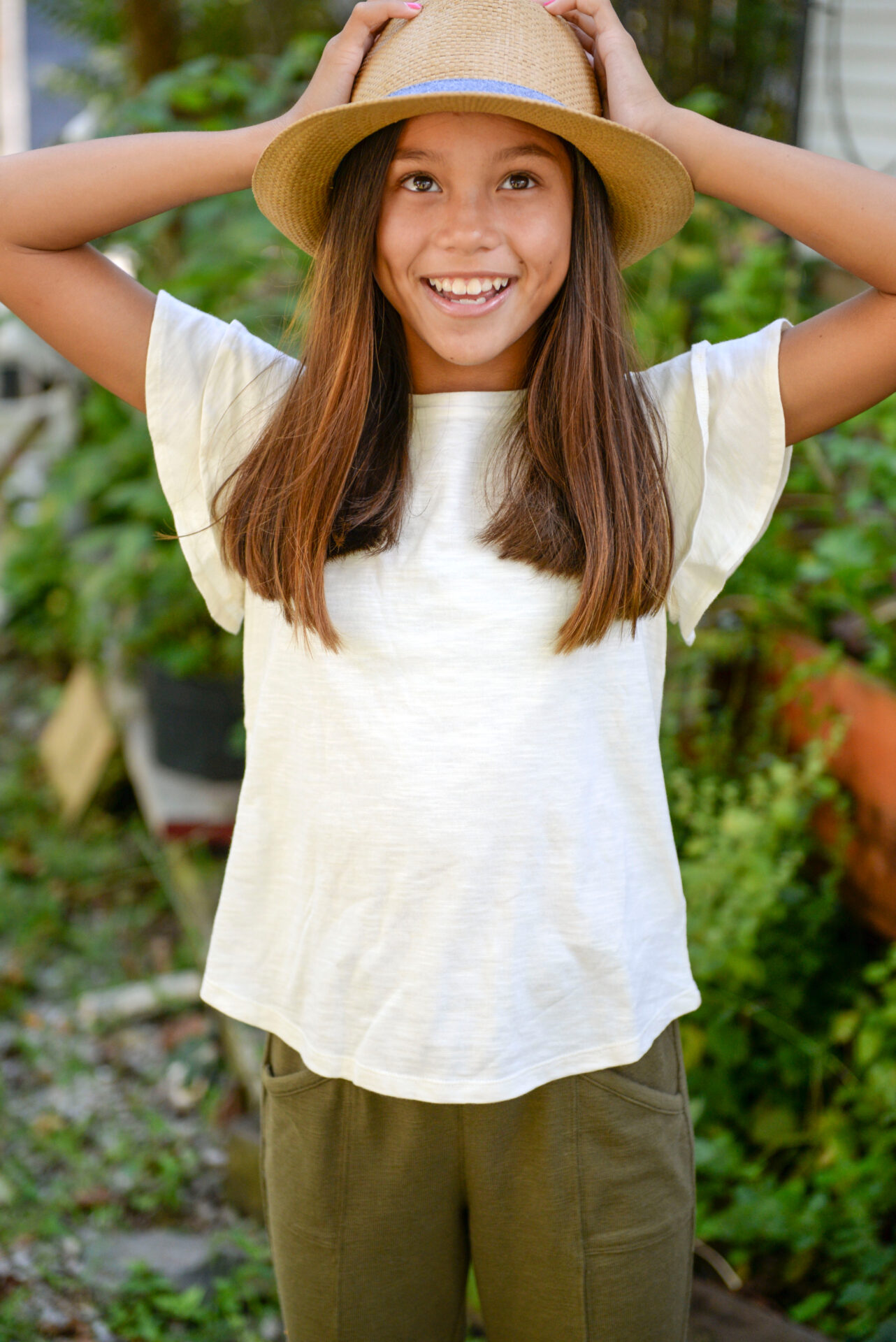 A smiling teen wearing a rattan bucket hat