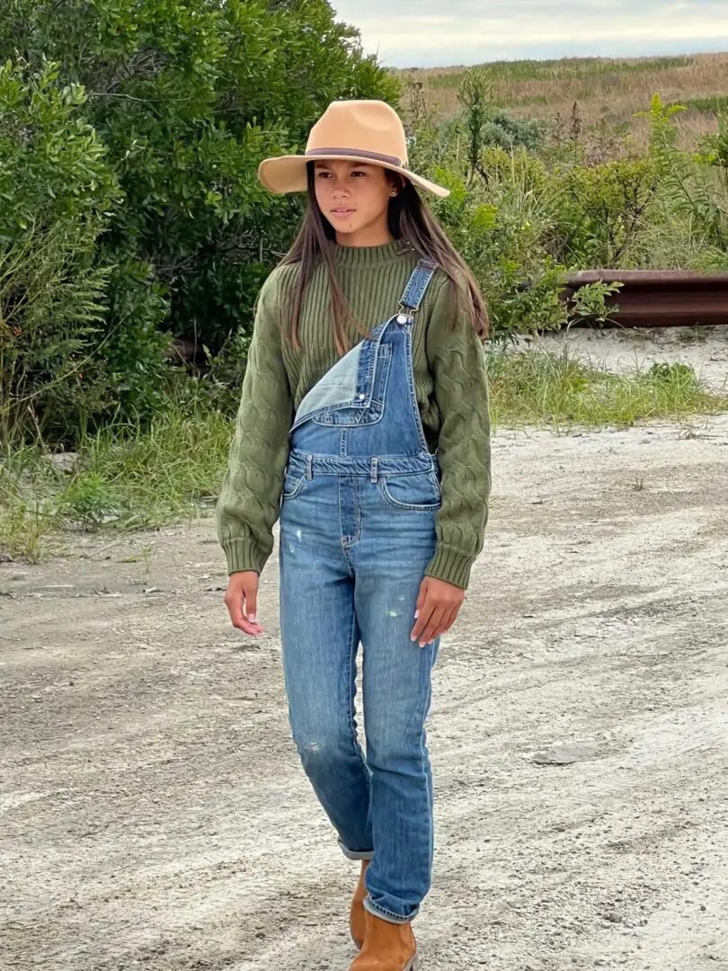 Caroline Quinn walking in a ranch wearing cowboy hat