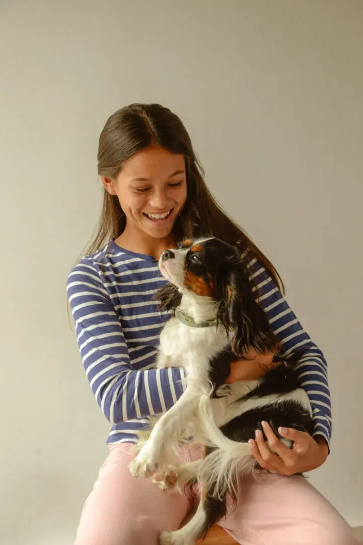 Girl holding a dog, smiling at the camera