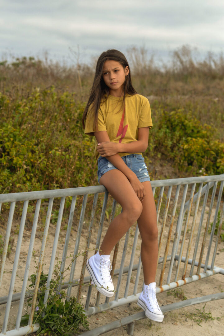 Girl sitting on a metal wall posing at the camera