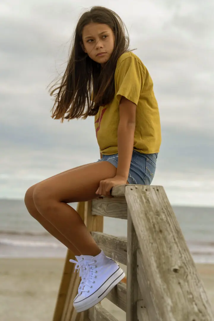Girl sitting on a wooden stand at the beach