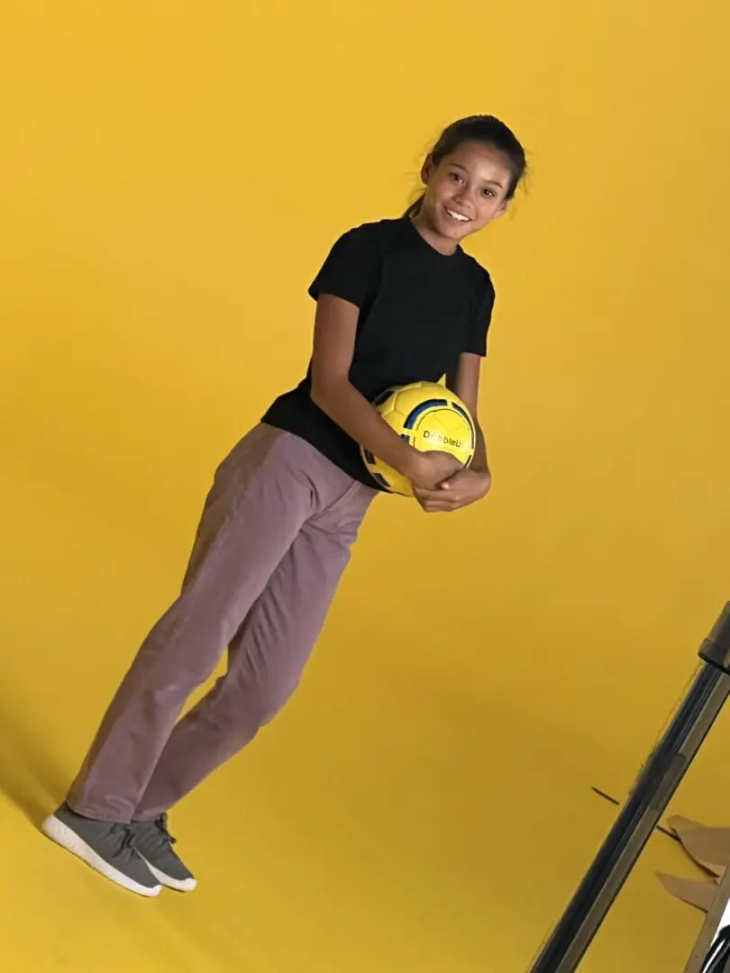 A girl holding a yellow color ball with yellow background