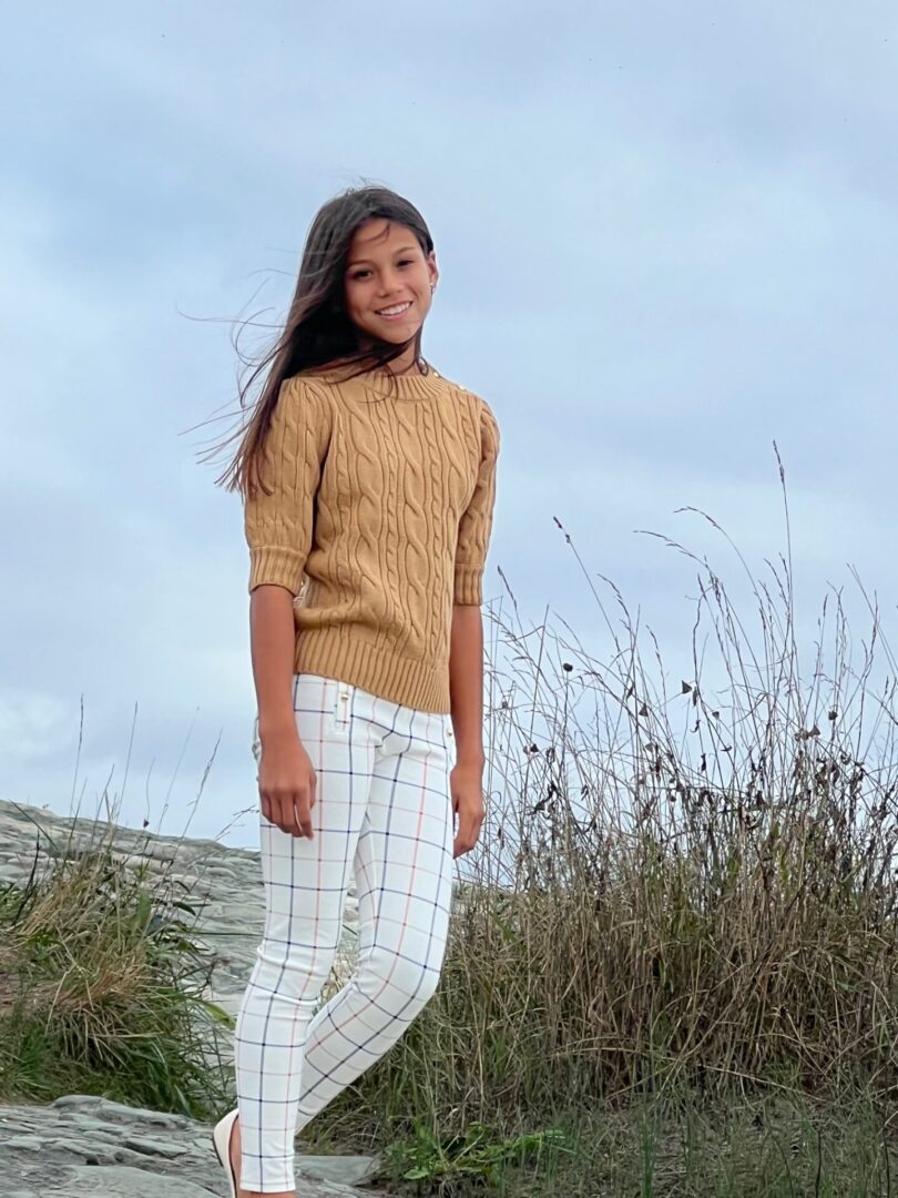 Caroline Quinn standing on rock wearing pant and brown top